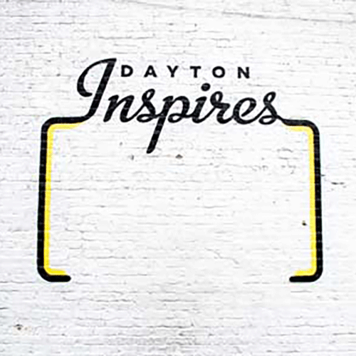 Dayton Inspires logo on white brick wall