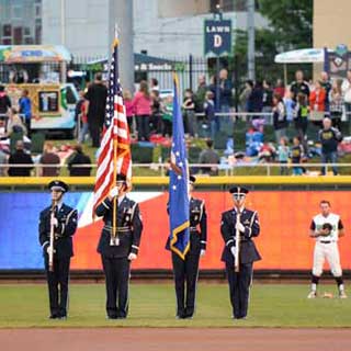 Vets holding flags at baseball game